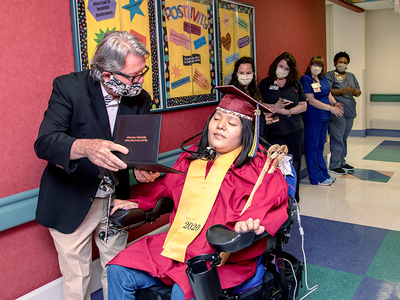 Teacher Ron Johnson from Choctaw Central High shows Deontay Isaac her high school diploma.